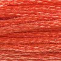A close-up view of embroidery thread skeins, held taught horizontally. The shade is a medium shade of orangey pink, like a fully-grilled salmon steak.