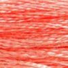 A close-up view of embroidery thread skeins, held taught horizontally. The shade is a medium light shade of orangey pink, like a salmon steak just thrown on the grill.