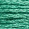 A close-up view of embroidery thread skeins, held taught horizontally. The shade is a medium green with a touch of grey, like Pistachio