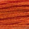 A close-up view of embroidery thread skeins, held taught horizontally. The shade is a medium pumpkin orange, like a freshly carved jack-o-lantern