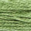 A close-up view of embroidery thread skeins, held taught horizontally. The shade is a medium light pure green, like pasture hills in the distance.
