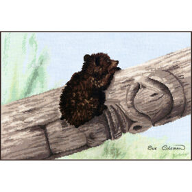 A tiny Brown Bear cub clings to the side of a fallen tree, which is carved into a half-completed totem pole
