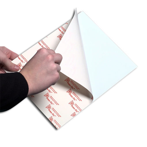 A pair of hands peeling back the wax paper layer on the sticky side of a mounting board